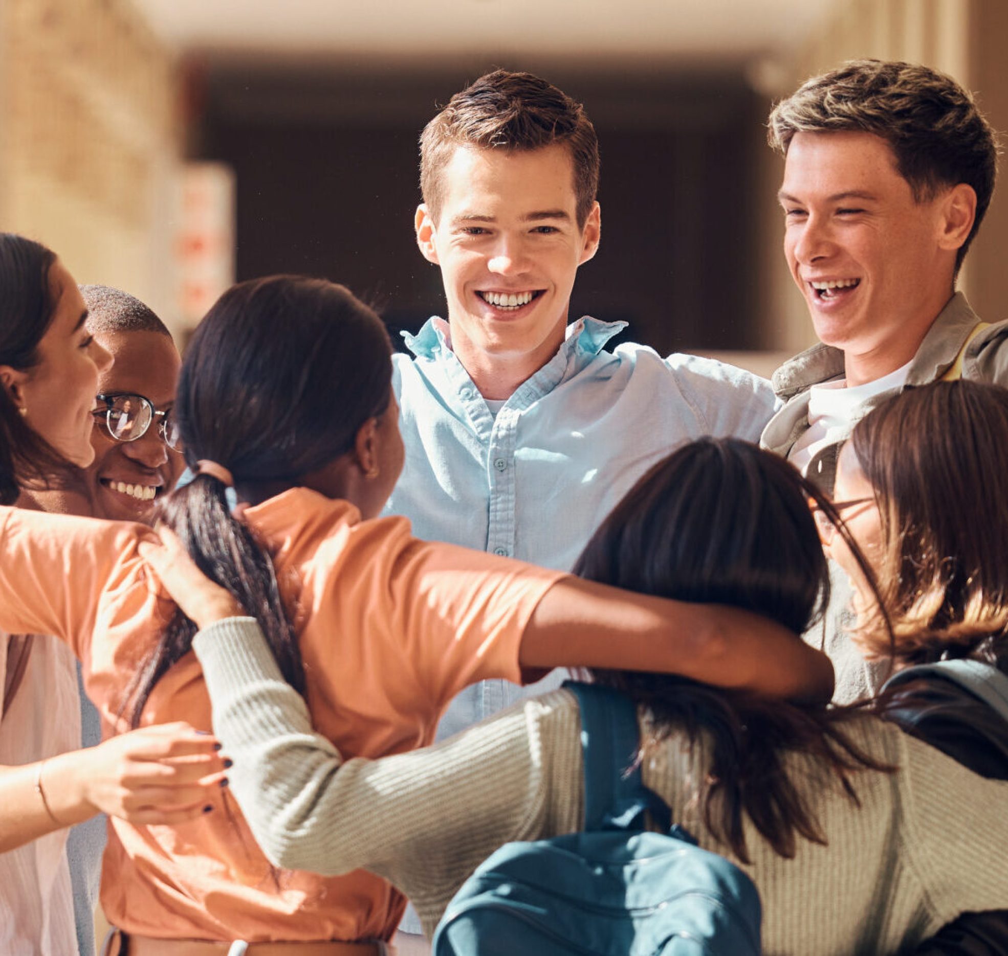 Group of people, happy students and hug for education celebration, interracial support or study project success. Diversity, university friends celebrate  and hugging happiness in building corridor